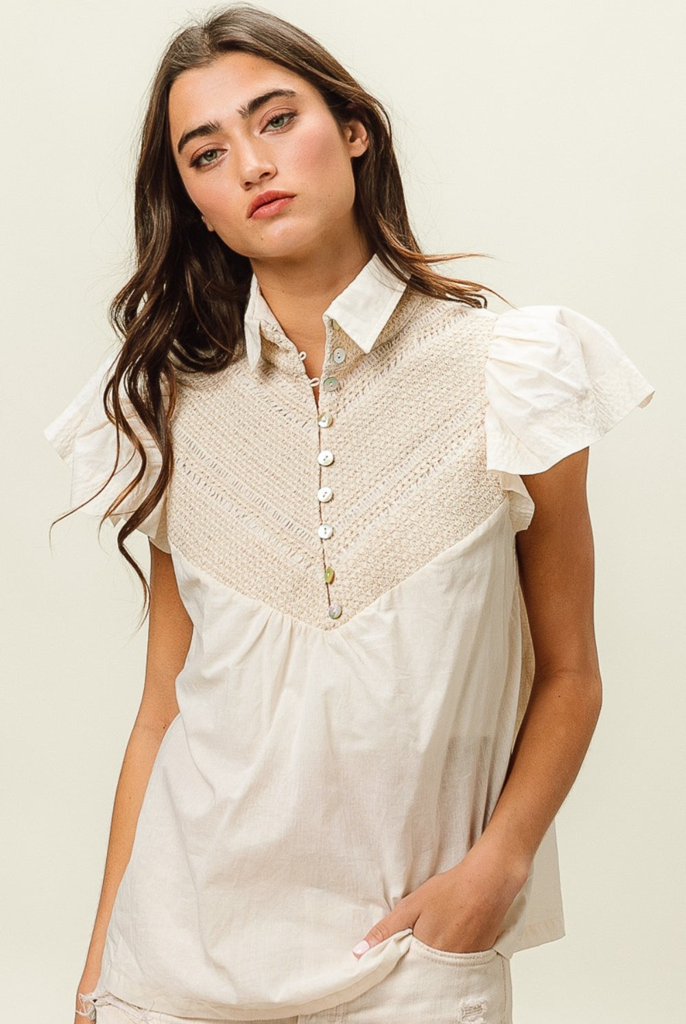 Woman wearing a beige short sleeve top with crochet panel and puff sleeves