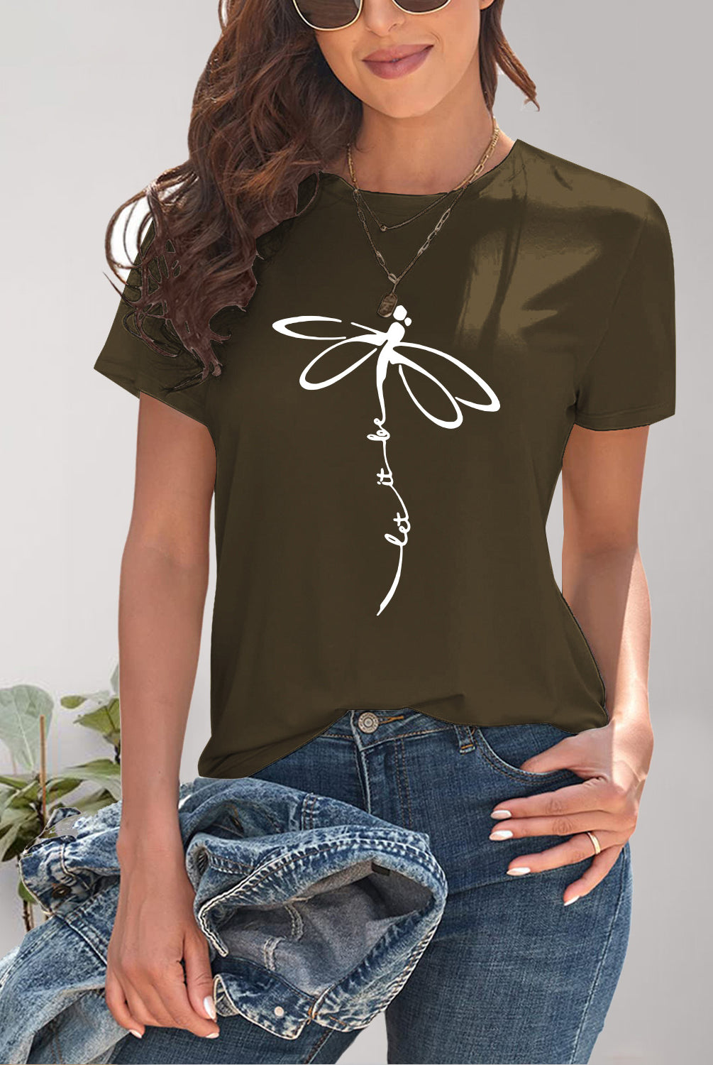 Fashionable woman wearing a black short sleeve tee featuring a bold dragonfly graphic, pairing it with casual denim for a day out.