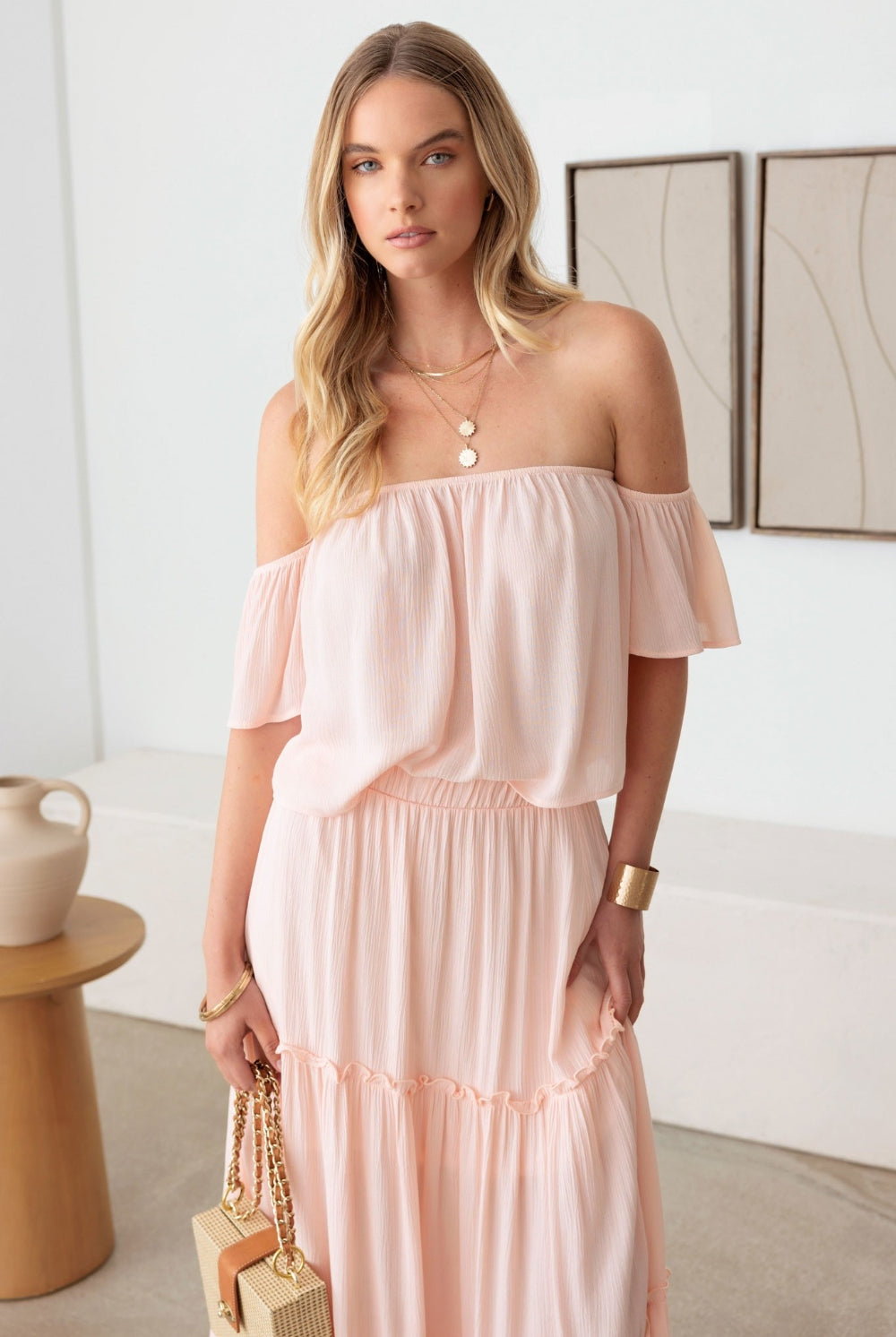 Elegant blush tiered dress with an off shoulder design and frill detailing, perfect for any occasion.