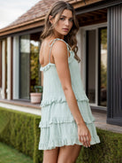 Woman in a mint green ruffled tiered dress with adjustable straps, ideal for spring and summer occasions.