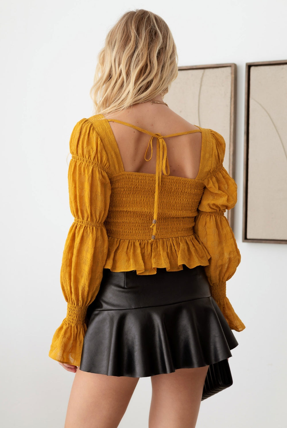 Fashion-forward woman in a mustard boho long sleeve top with delicate ruffle detailing, embodying an effortlessly chic style.