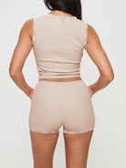 A model showcasing a sophisticated strap top with delicate lace trim and matching shorts, exuding casual elegance.