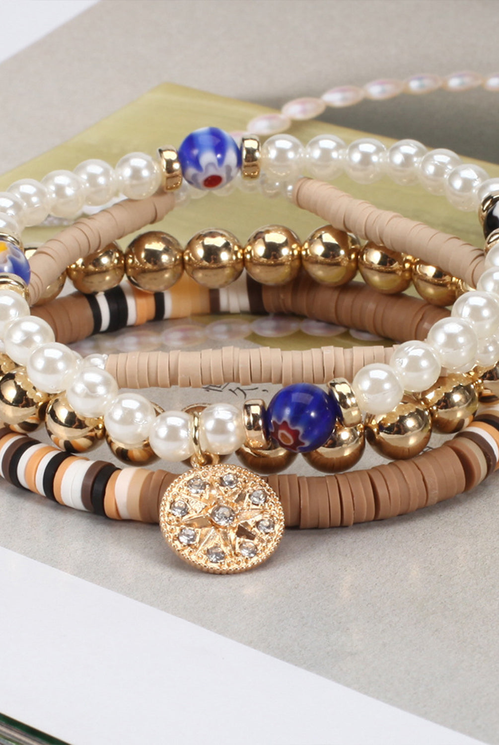 Elegant soft pottery bead bracelet with pearls, gold spheres, and a central sparkling charm.