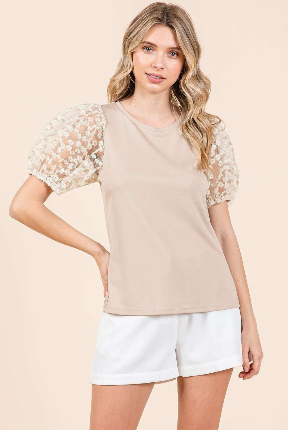 A woman wearing a stylish taupe top with puff sleeves, combining modern elegance with classic comfort, perfect for versatile styling.