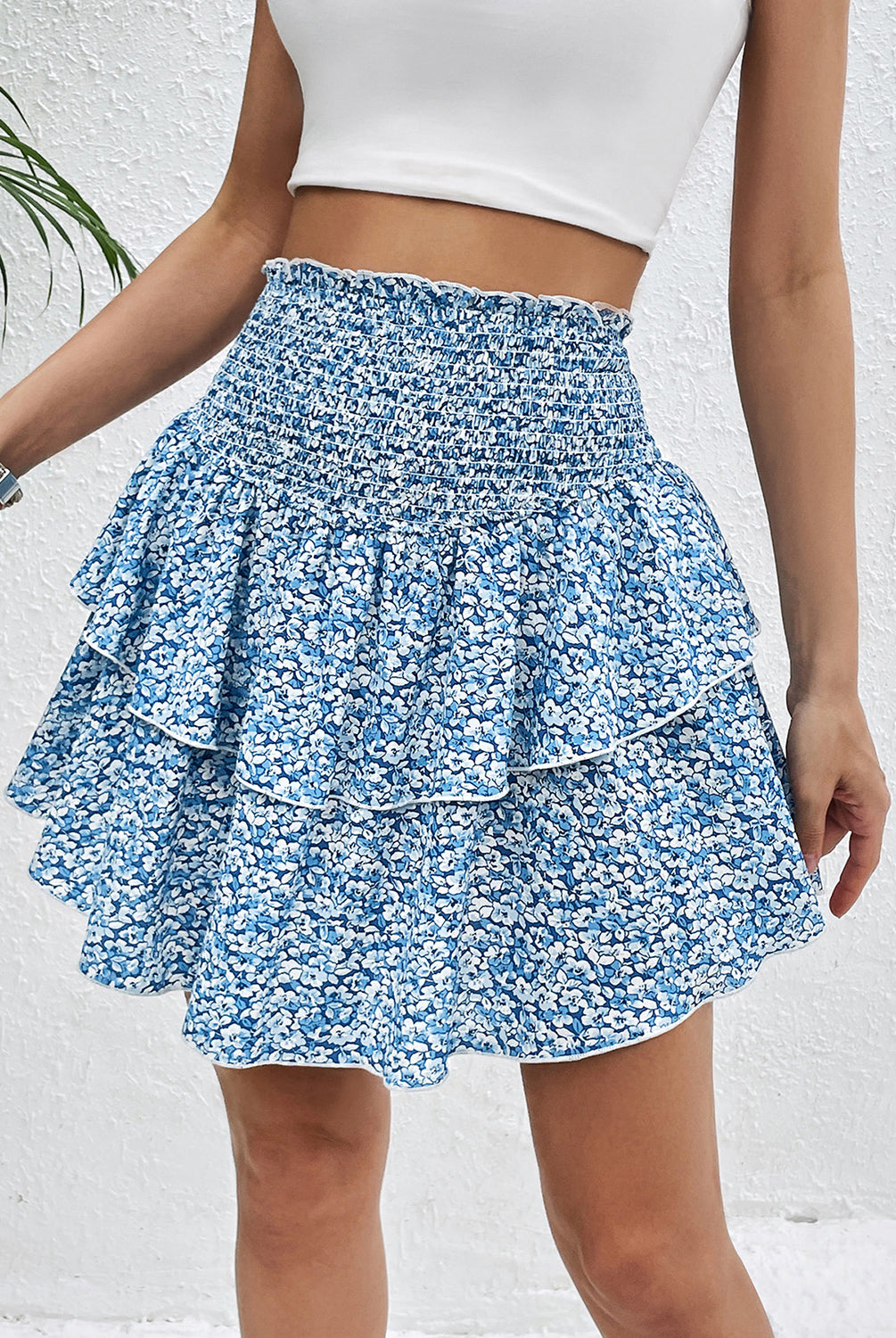Woman wearing a printed layered smocked sky blue mini skirt with a white crop top.