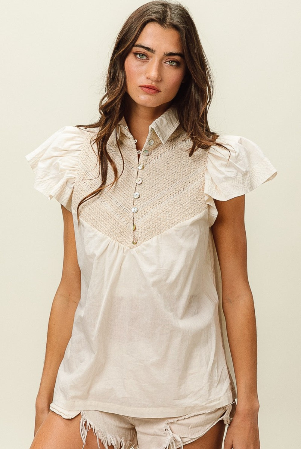 Woman wearing a beige short sleeve top with crochet panel and puff sleeves