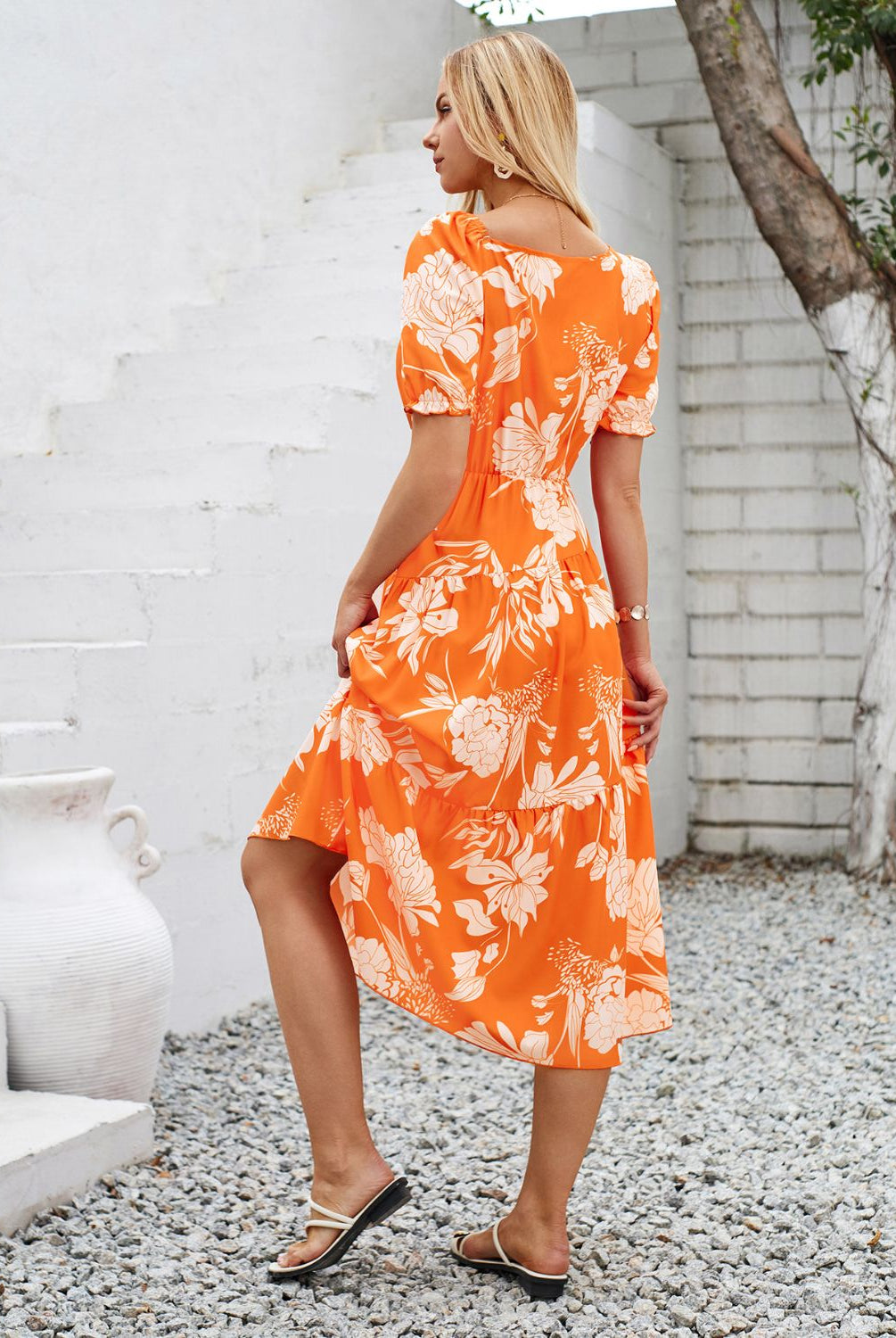 Woman in a vibrant orange floral printed midi dress, perfect for summer.