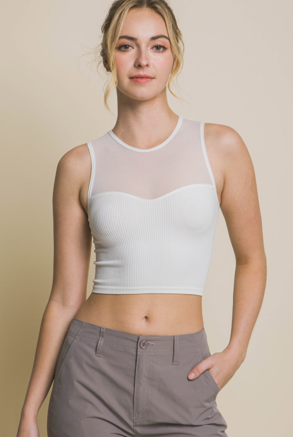 Trendy woman in a sleek white crop tank top with mesh detailing, pairing effortlessly with casual trousers from GemThreads Boutique.  Search Engine Listing Page Title: