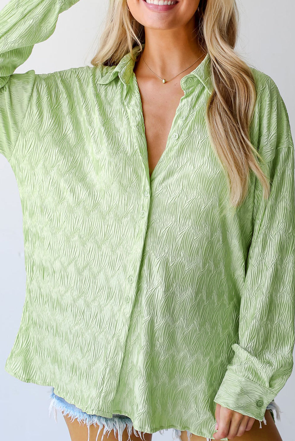 A light green, long-sleeve shirt with a distinctive textured pattern, offering a button-down front and a casual fit. Worn by a woman with blonde hair, it's styled with denim shorts, with the photo capturing from the waist up.