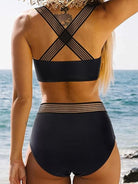 A woman radiates summer chic in a pink high-waist bikini set with stylish black stripe accents, perfect for a day at the beach or pool.