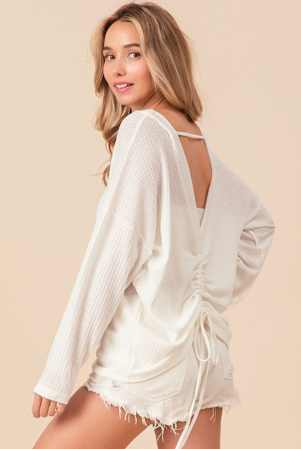 A relaxed-fit, waffle-knit top with long sleeves and an adjustable tie-back detail, blending comfort with a hint of allure.