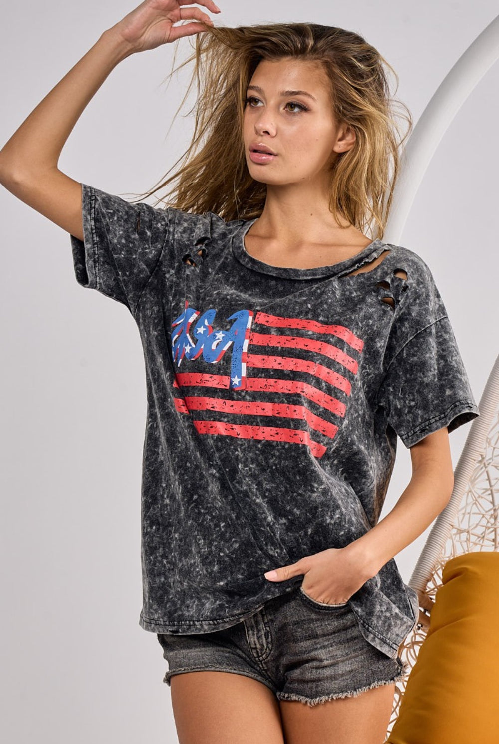 Smiling woman in a trendy American flag-themed t-shirt, embodying a casual and patriotic style.