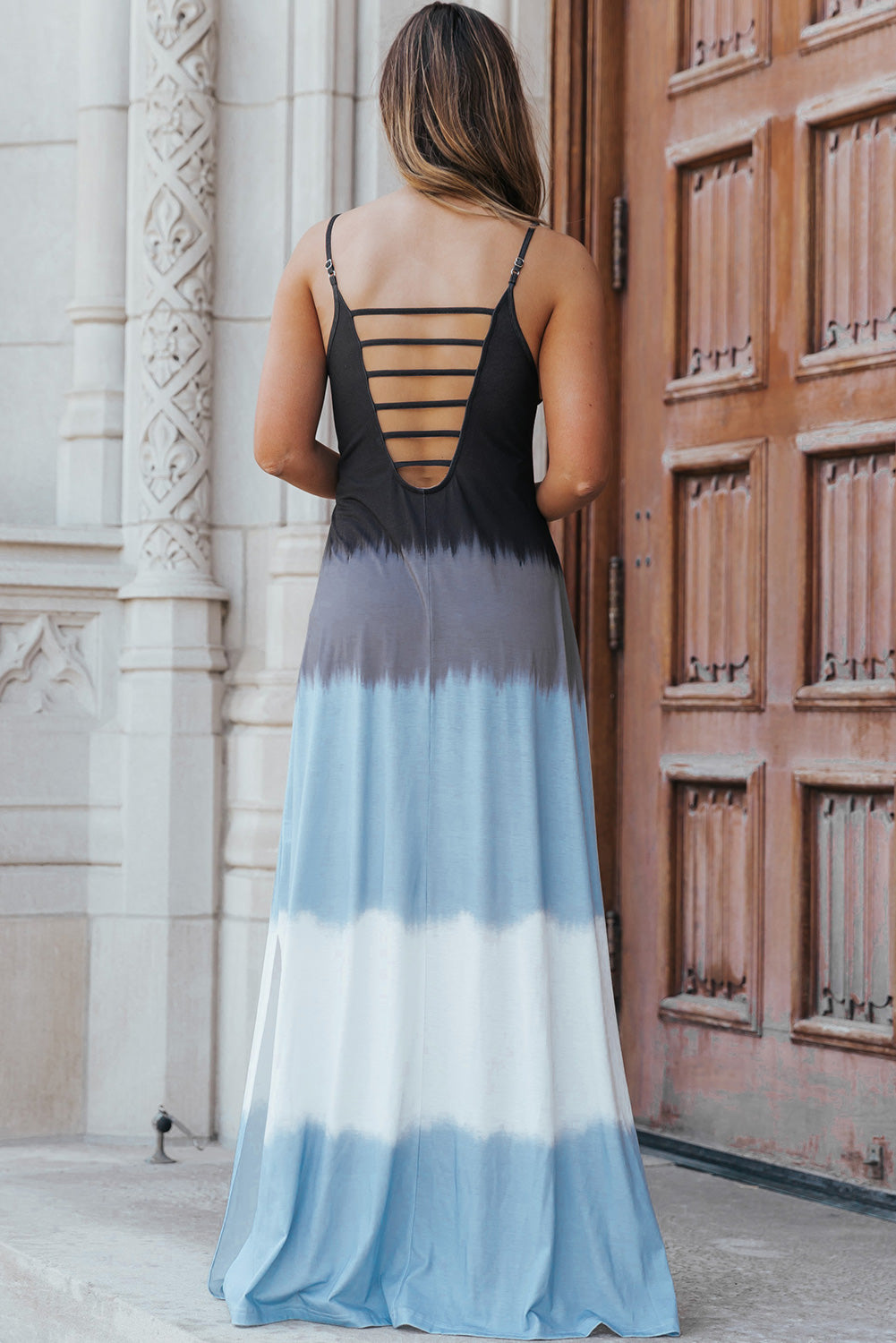 Stylish woman wearing a color block scoop neck maxi dress with a side slit, featuring blue and black tones.