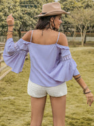 Smiling woman twirling in a purple flare sleeve top with lace accents
