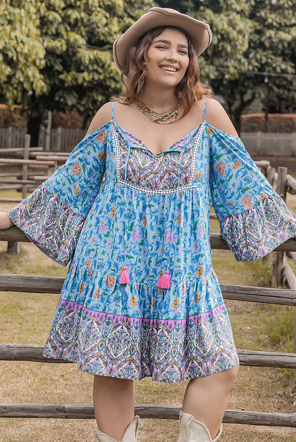 Woman wearing a plus size printed mini dress with long sleeves, featuring coral and sky blue colors, standing outdoors.