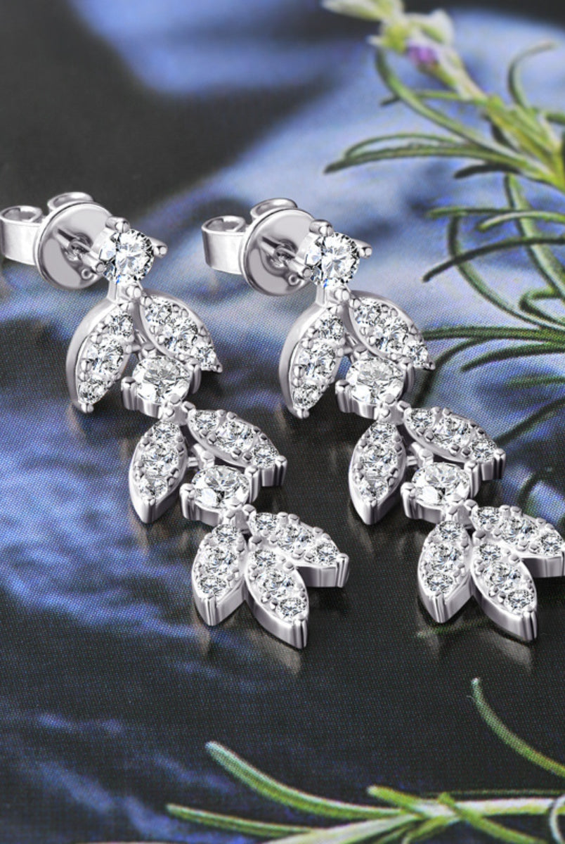 Close-up of a woman wearing elegant sterling silver leaf-shaped earrings, reflecting a subtle sparkle.