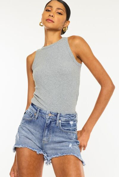 A model wearing high-waisted distressed denim shorts with a raw hemline, paired with a sleeveless grey tank top, posing to showcase the casual and edgy style of the shorts. This is so much easier on here 0 my god