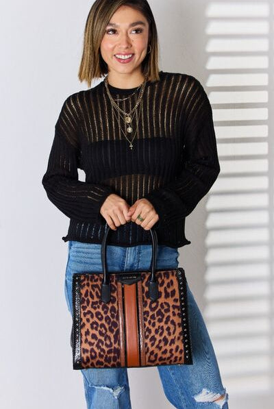A stylish leopard print tote bag with black and tan accents, carried by a woman in a chic black knit sweater and denim jeans.