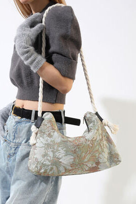 Side view of a woman carrying a leopard print hobo bag with a tassel detail, paired with a white fluffy sweater and light-wash denim jeans.