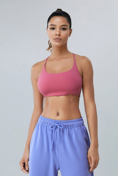Fit model showcasing the Berry Pink VersaFit Sports Bra, highlighting its smooth design and supportive fit, paired with light blue casual joggers.