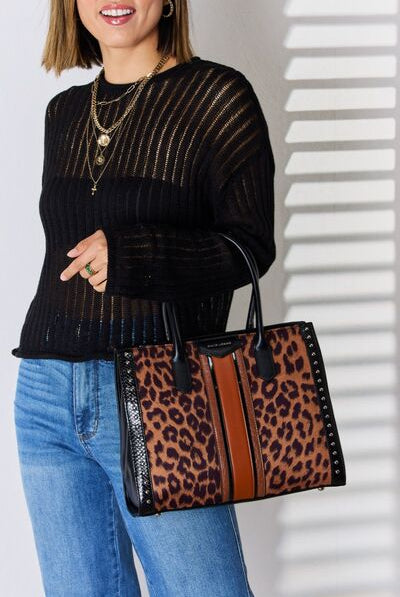 A stylish leopard print tote bag with black and tan accents, carried by a woman in a chic black knit sweater and denim jeans.